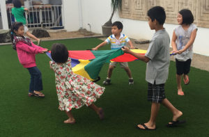 Dharma School children in ring holding a multicolored fabrc